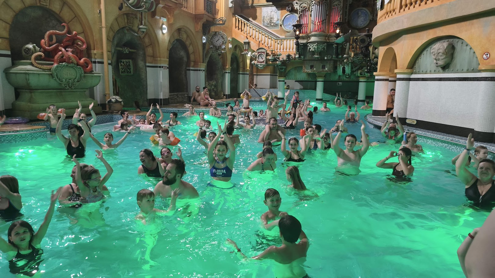 Aqua animace – děti i dospělí cvičí ve vodě s rukama nahoře